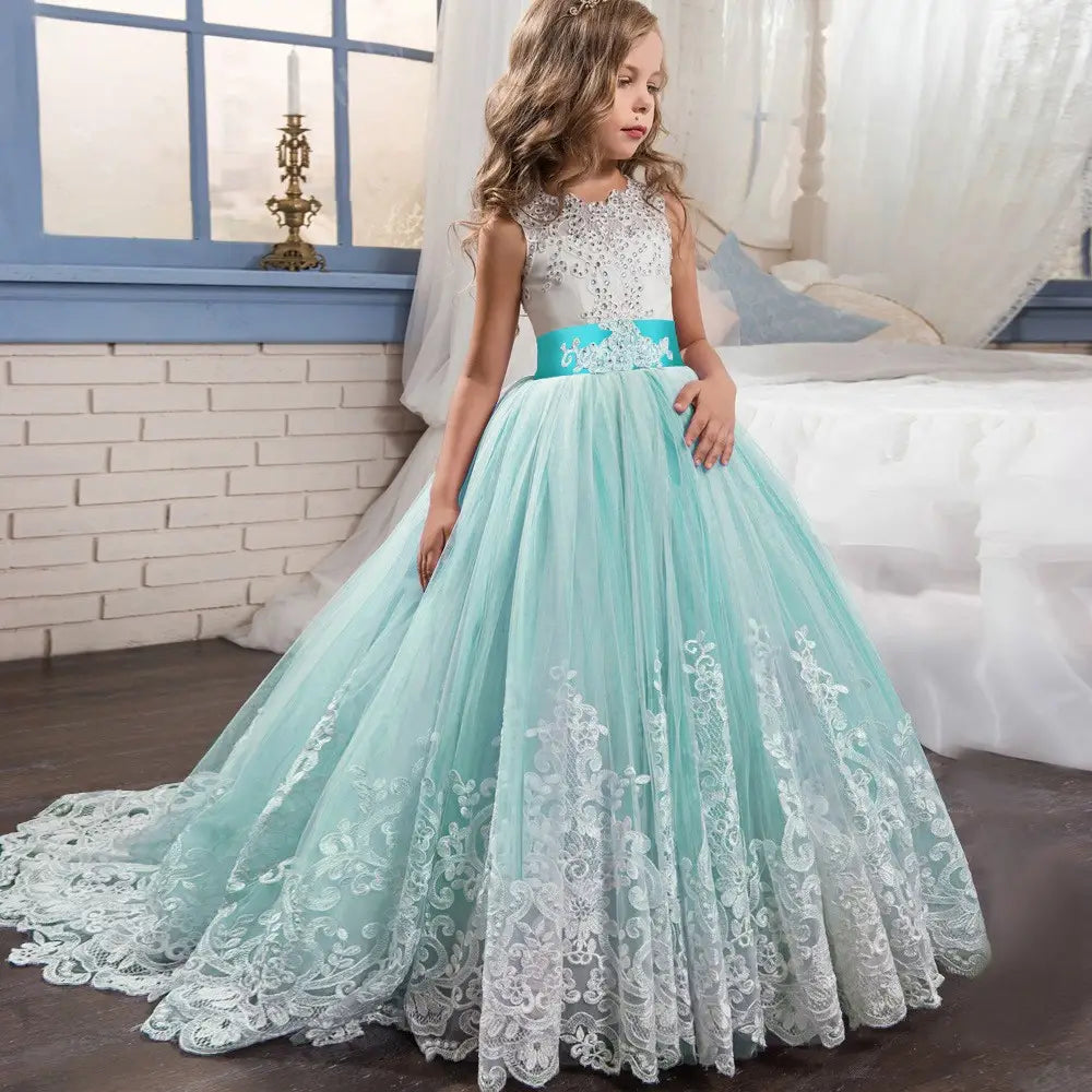 Ein junges Mädchen trägt ein minzgrünes und weißes Spitzenballkleid mit verziertem Mieder, Satin-Schärpe und fließendem Tüllrock in einem mit Stickspitze verzierten Tüllblumenmädchen-Prinzessinnenkleid.