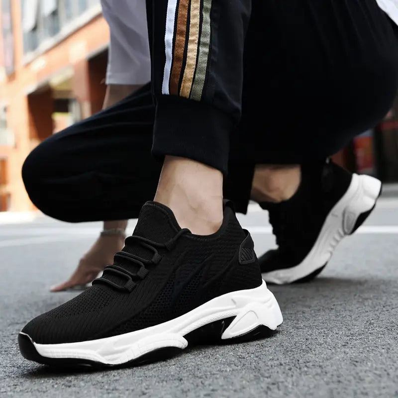 Men’s air cushion running shoes featuring black knit sneakers with a thick white rubber sole and subtle side branding.