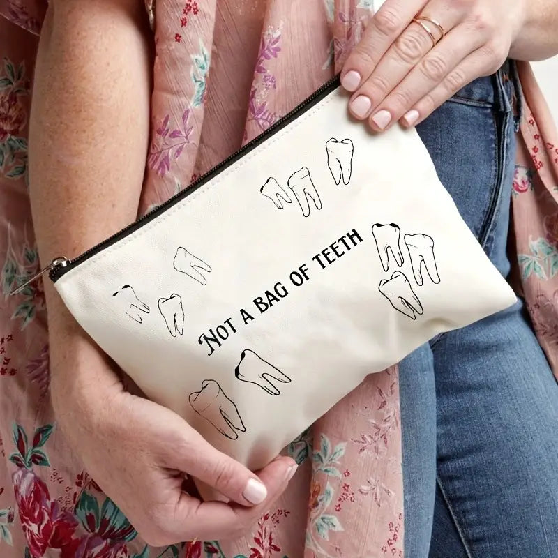 Cream-colored canvas zipper pouch featuring black line-drawn teeth and the text not a bag of teeth designed as a travel case.