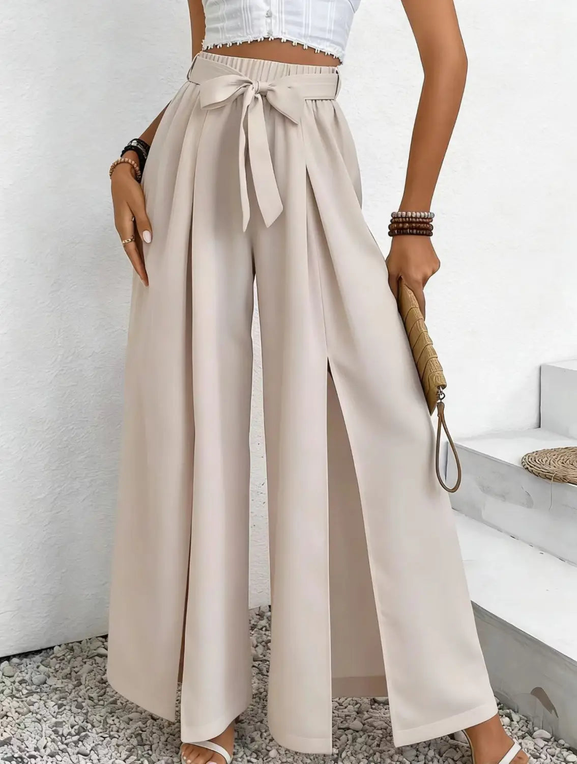 Pantalon ample à taille haute beige avec une ceinture en tissu assortie nouée en nœud à la taille, conçu comme un pantalon ample et décontracté.