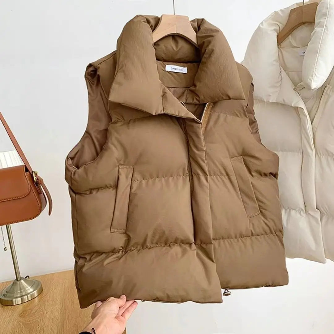 A cozy tan women quilted puffer vest featuring a plush quilted design and two front pockets perfect for loose sleeveless outerwear.