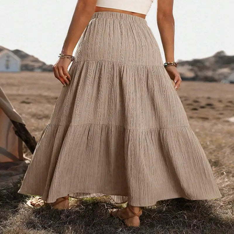 Beige tiered maxi skirt with textured crinkled fabric and elastic waistband designed for lightweight casual wear.