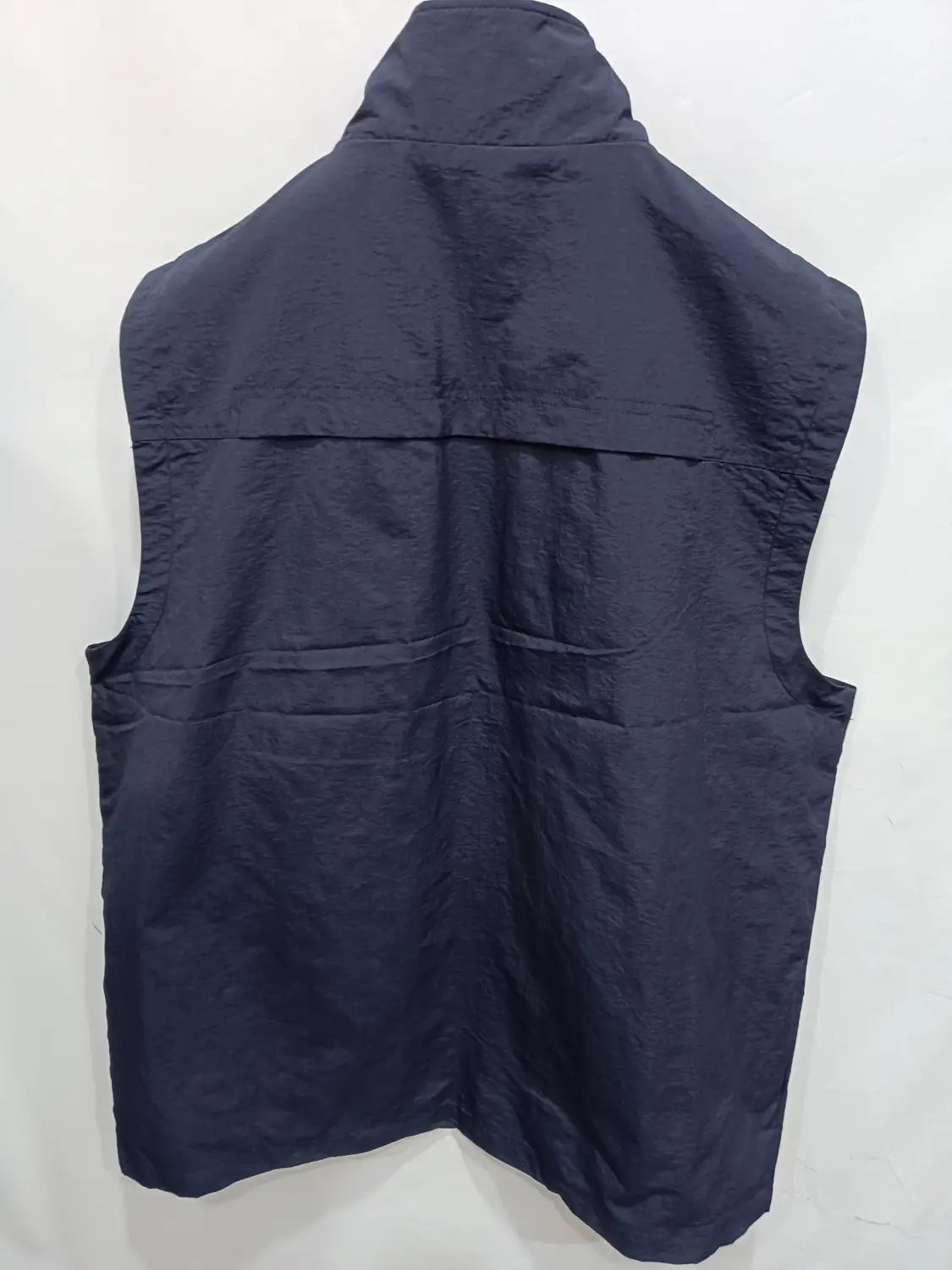 Chaleco utilitario con capucha y múltiples bolsillos para hombre en azul marino oscuro, diseño sin mangas, con cuello alto y dos bolsillos frontales.