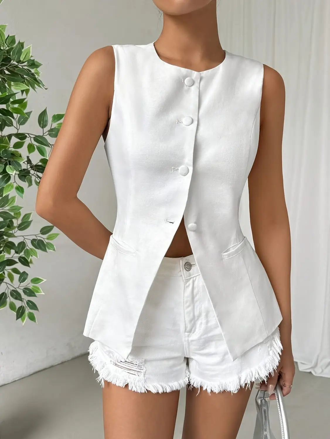 Veste sans manches à volants peplum blanche, haut boutonné avec poches avant, associée à un short en jean blanc assorti présentant des ourlets effilochés.