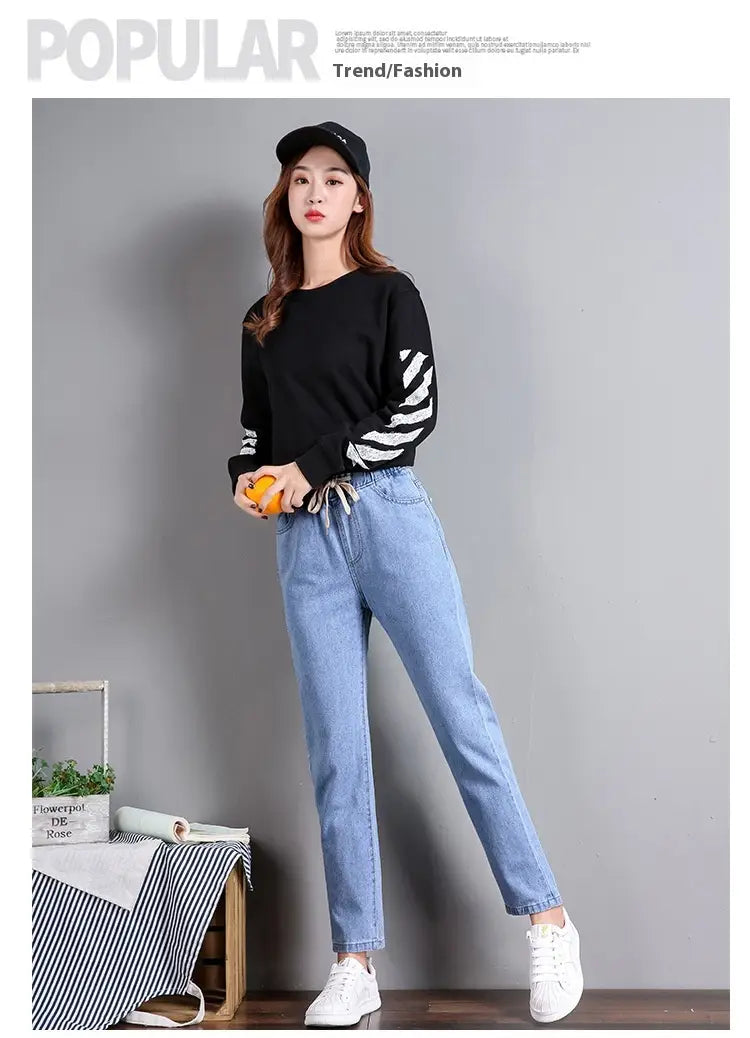 Pull noir à manches longues avec poignets rayés et taille à cordon de serrage, associé à un jean droit taille haute style coréen présenté de face