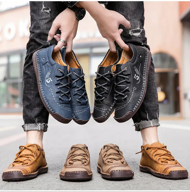 Ein Paar Herren-Casual-Lederschuhe im britischen Stil aus dunkelblauem und schwarzem Leder mit sichtbaren Kordel-Schnürsenkeln und einem kleinen bestickten Logo an der Seite.