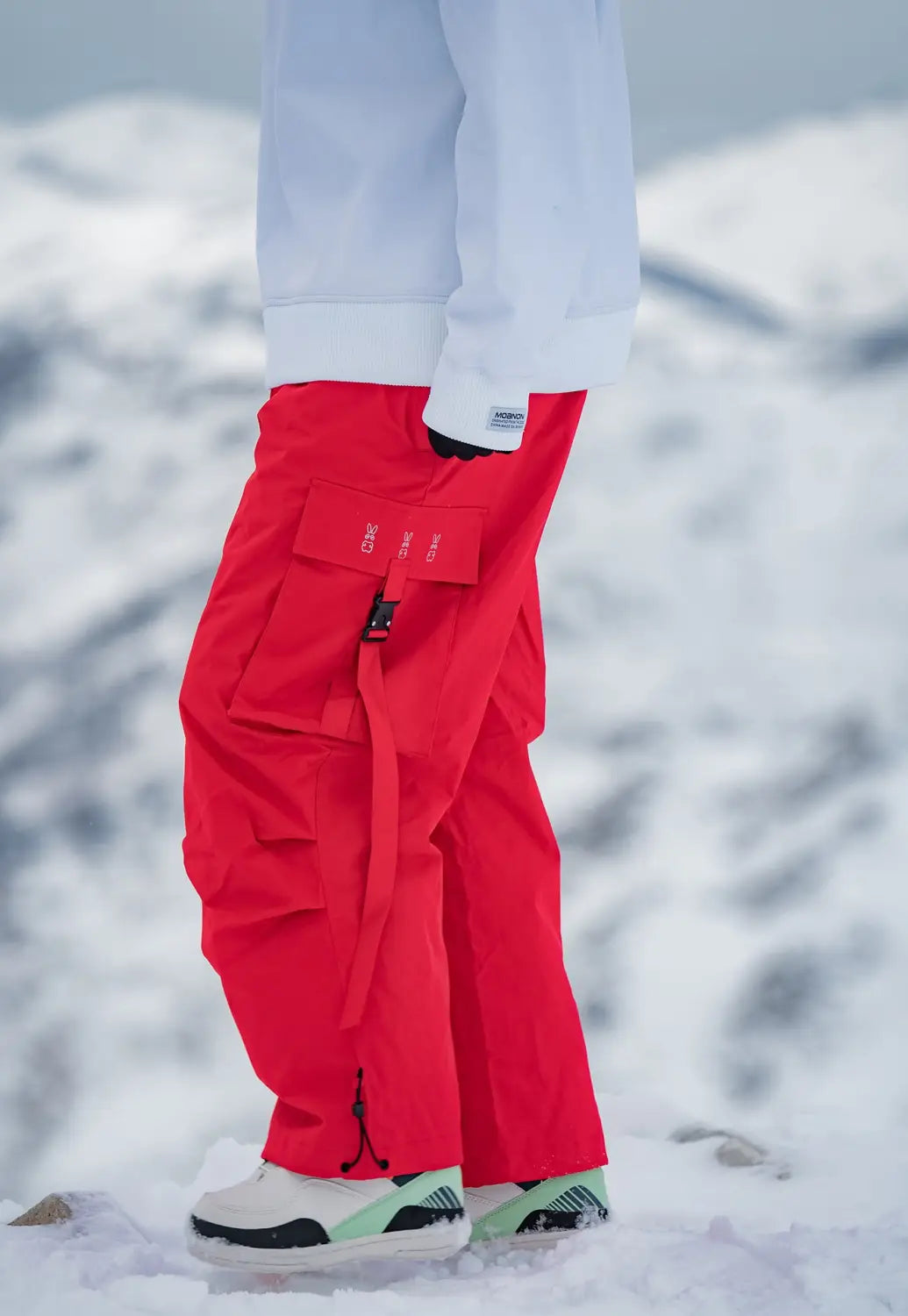 Bright red winter outdoor loose ski pants featuring a bold functional design with cargo pockets and subtle branding on the thigh pocket.
