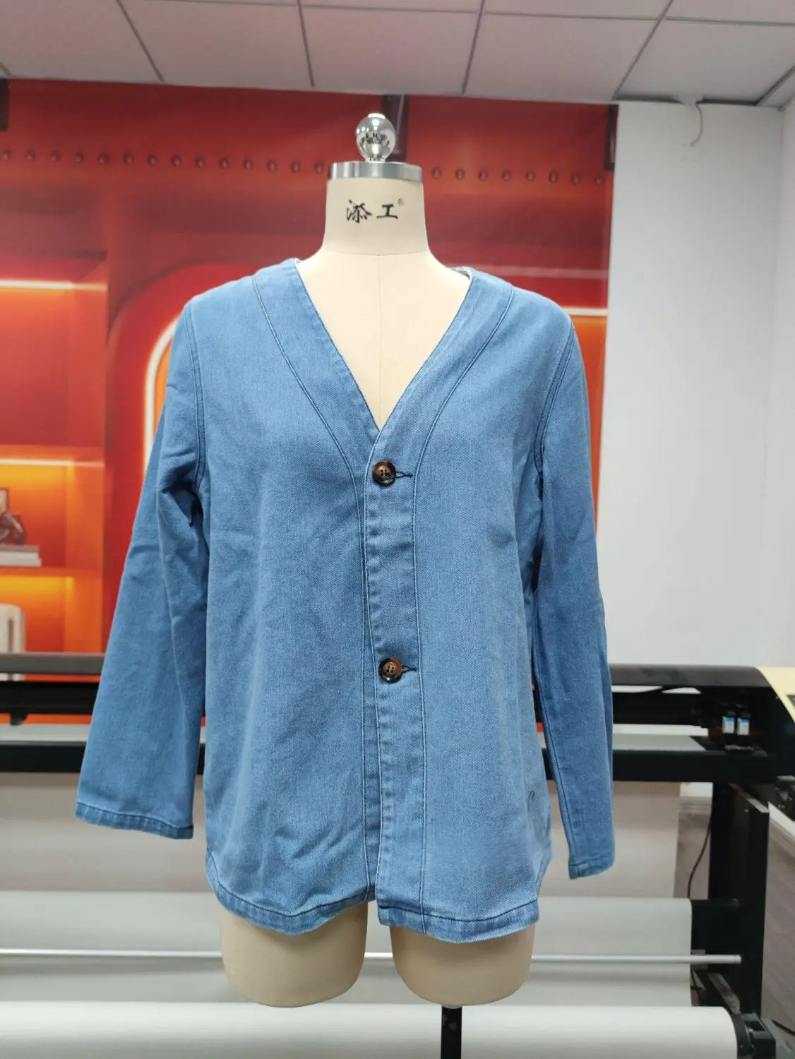 Chaqueta tipo cárdigan de mezclilla azul claro para mujer con cuello en V y tres botones marrón oscuro en la parte delantera.