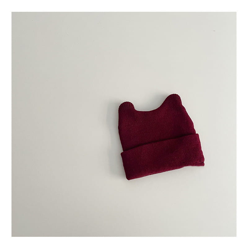 A cozy maroon knitted childrens beanie hat featuring soft rounded ear-like protrusions designed as a warm winter cap.
