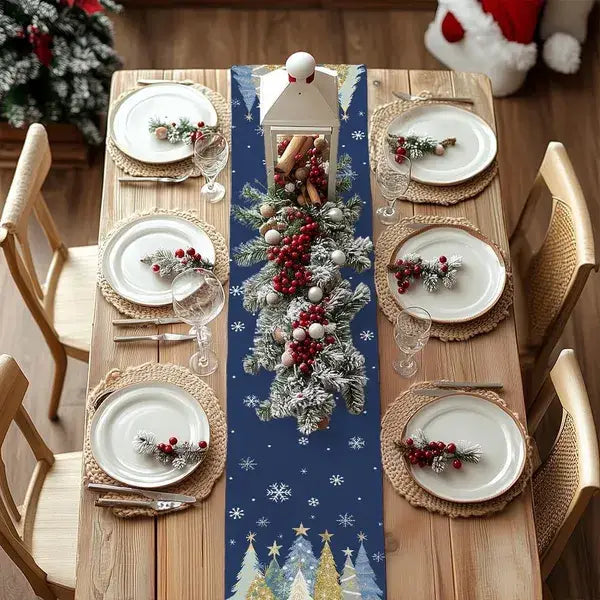 Chemin de table de Noël 13 x 72 bleu marine avec des sapins enneigés et des flocons de neige, présentant un tissu bleu festif orné de branches de pin givré, de baies rouges, de décorations argentées et de motifs de flocons de neige.