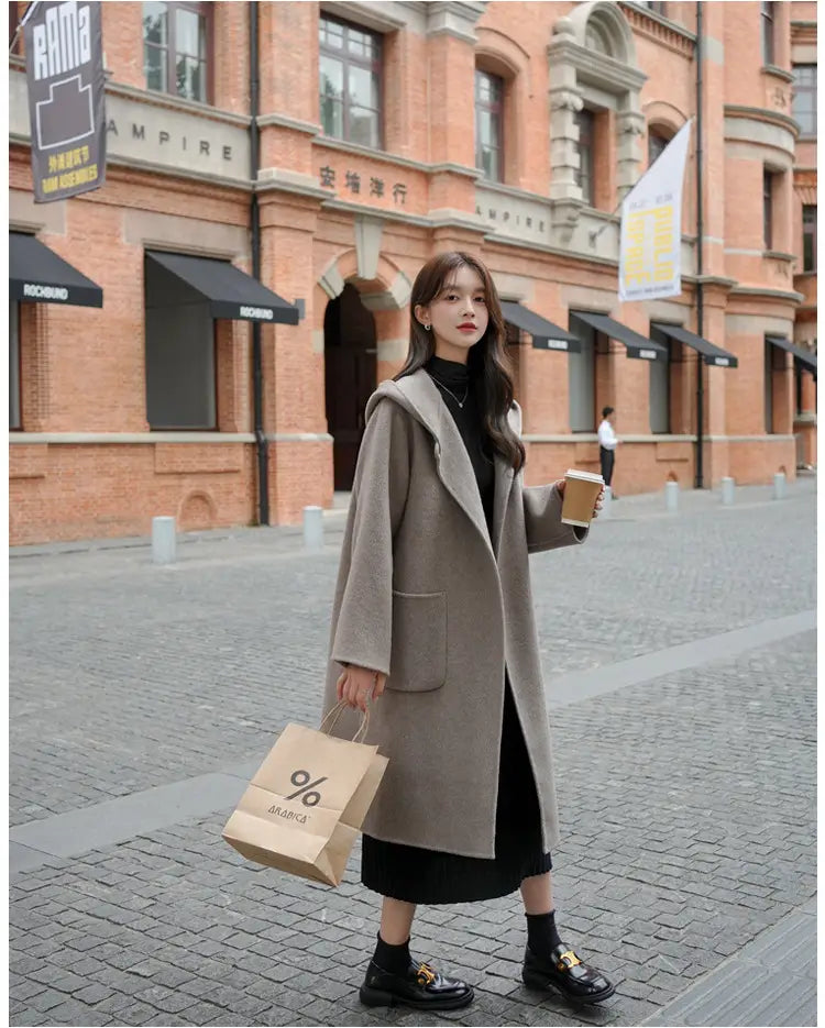 Beiger Wollmantel mittlerer Länge mit Kapuze und vorderen Taschen, entworfen für Winter-Outdoorbekleidung.