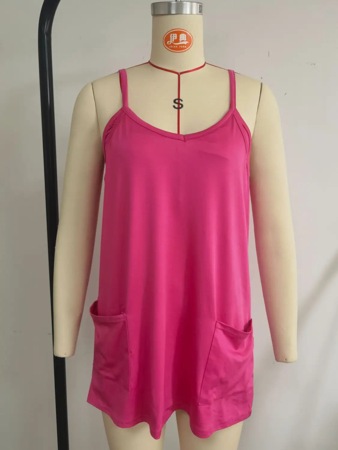 A vibrant pink sleeveless camisole dress with thin straps and two front pockets displayed on a mannequin as part of a women casual romper and strap top set.