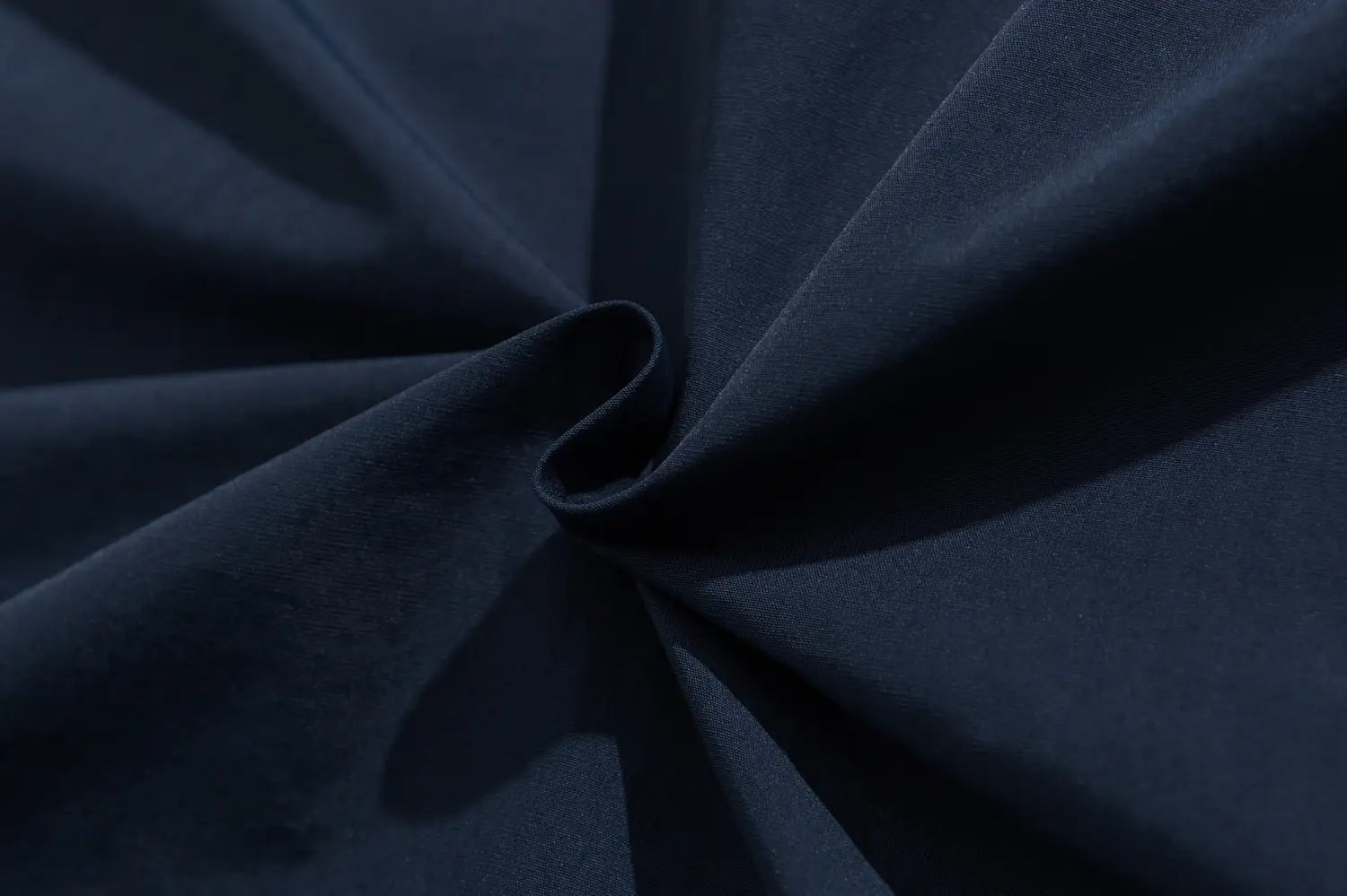 Tissu bleu marine foncé à la surface douce légèrement texturée, présenté dans une veste coupe-vent ample à blocs de couleurs brodés.