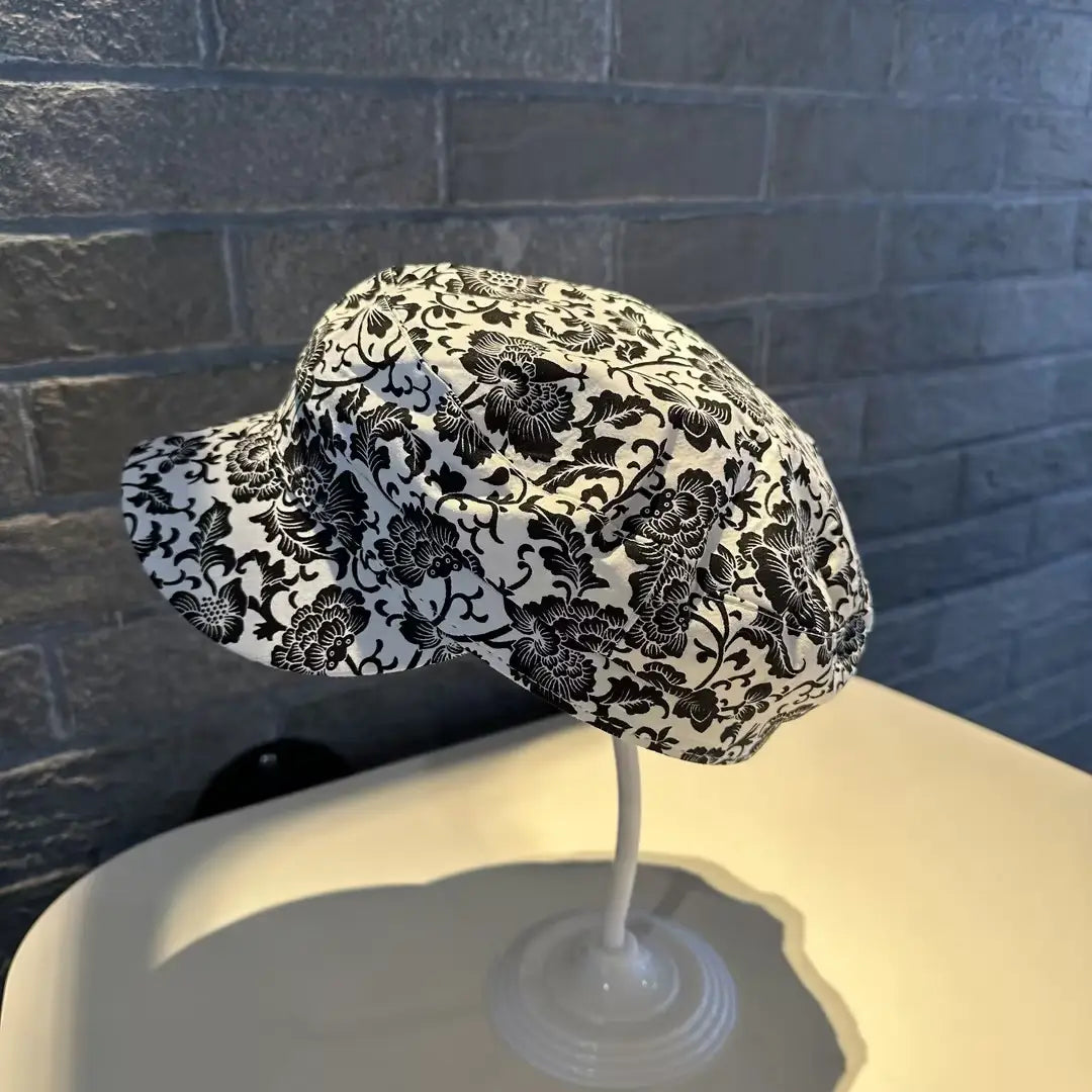 Gorra tipo bucket hat de tela con patrón floral negro y blanco con ala ancha, en diseño de gorra estilo coreano, impresa.
