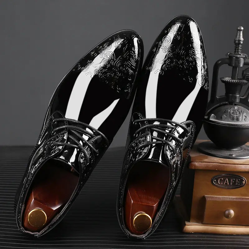 Embossed patent leather men’s formal business shoes in black feature a glossy finish and intricate white swirl patterns on the toe cap.
