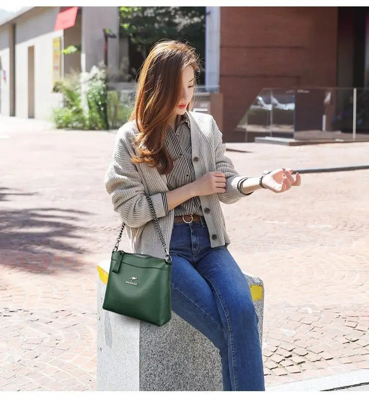 Dark green leather crossbody handbag with silver chain strap and small front logo.