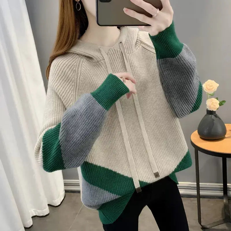 Ein gemütlicher Colorblock-Strickhoodie für Damen mit einem beigen Oberteil und lebendigen grünen und grauen Akzenten an den Ärmeln und am Saum.