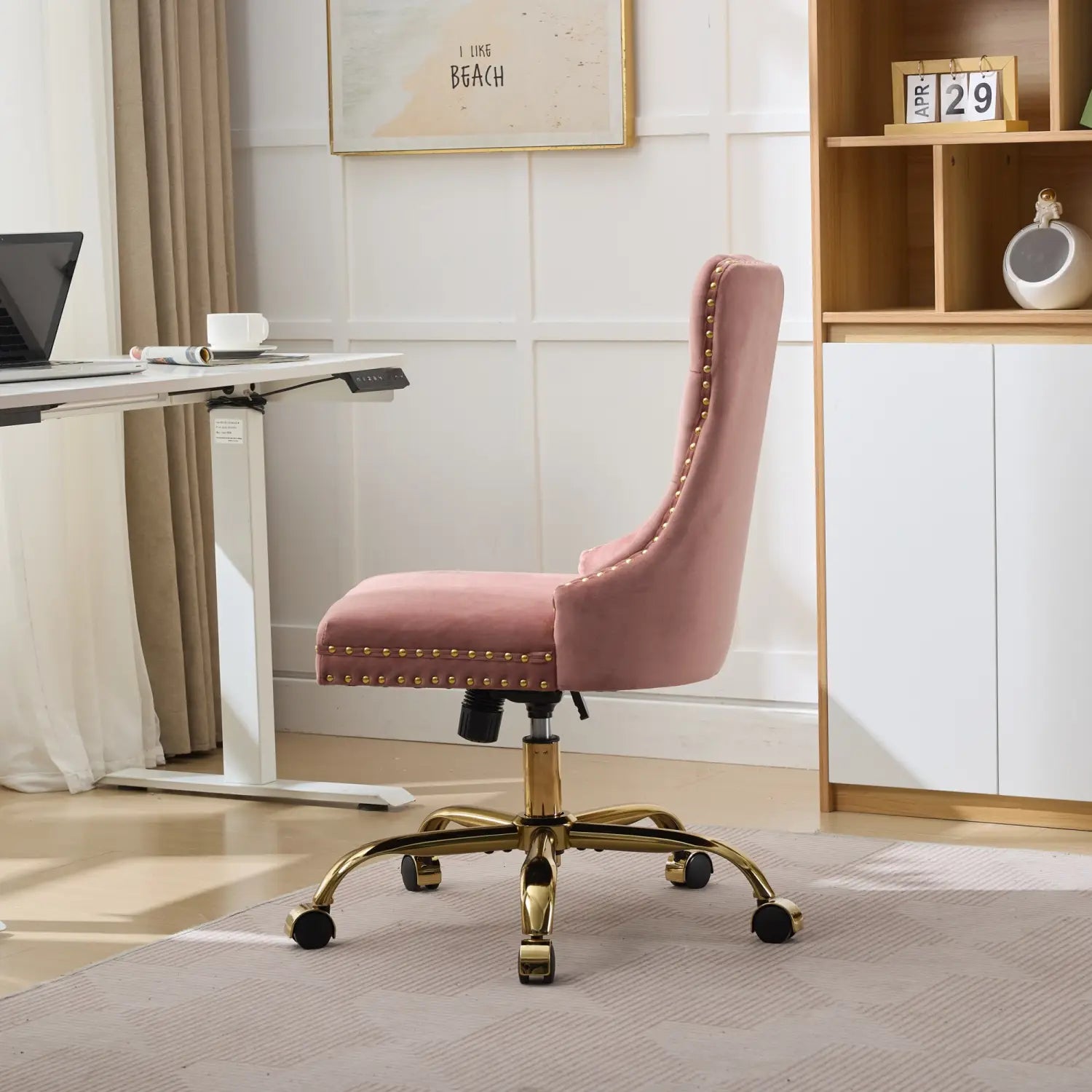 Fauteuil de bureau en velours rose poudré à capitonnage avec monture métallique ton doré et bordure à clous décoratifs, présenté depuis l’arrière.