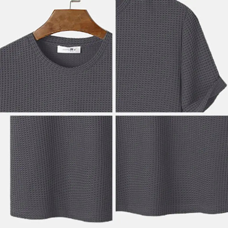 Herren-T-Shirt in Slim-Fit aus Waffelstrick als Henley in Dunkelgrau mit kurzen Ärmeln, auf einem Holzkleiderbügel hängend.