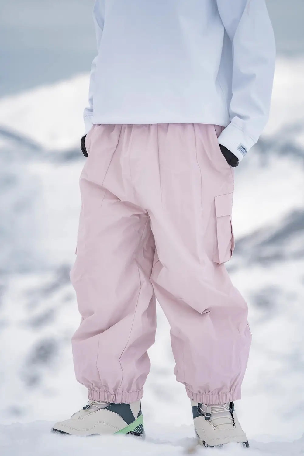 Winter outdoor loose ski pants in pink waterproof material with elastic cuffs and side pockets designed for cold weather activities.
