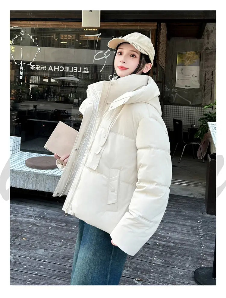 Veste courte matelassée à capuche pour femme couleur crème avec poches avant, conçue pour apporter de la chaleur en hiver.