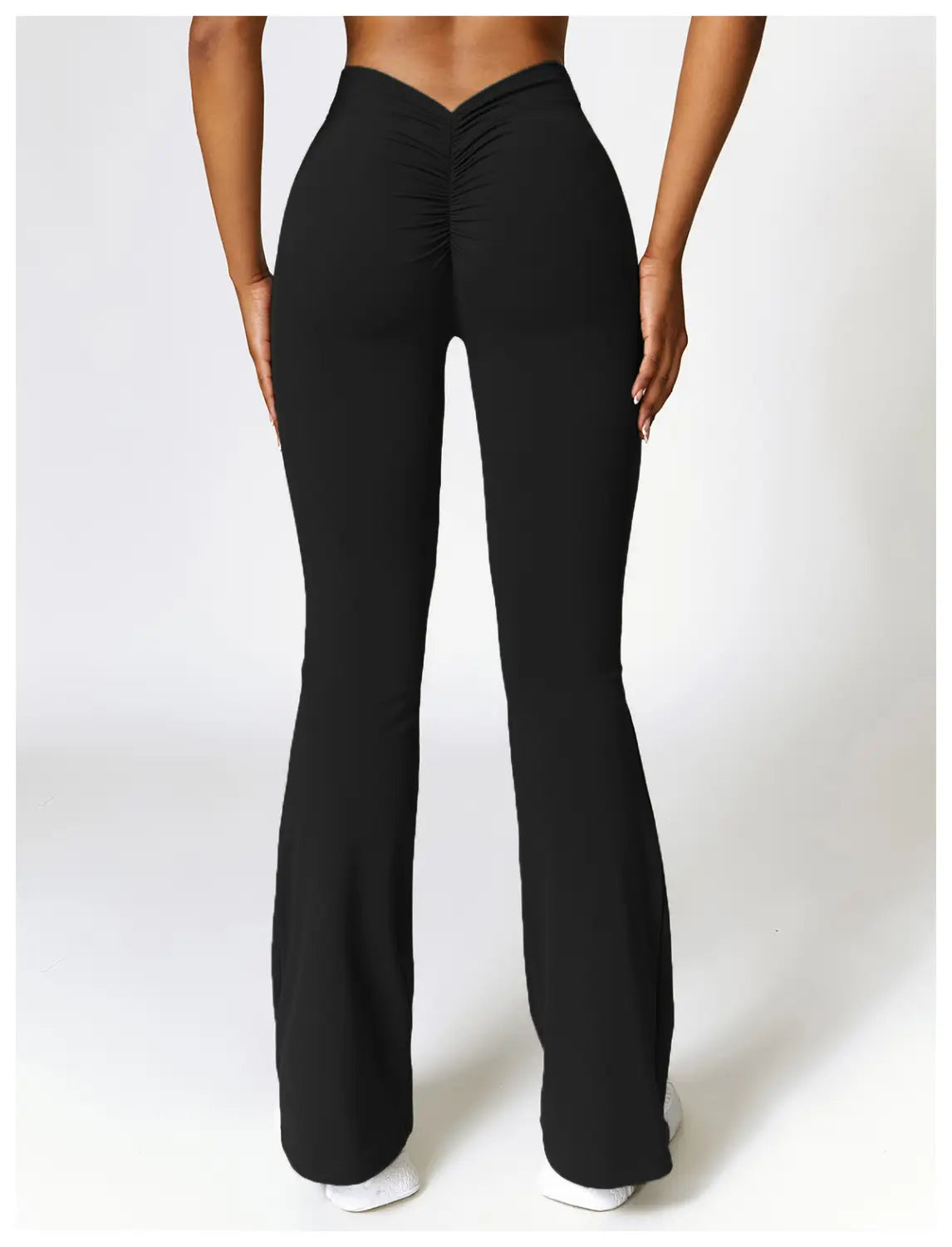 black high-waisted flared yoga pants with a ruched back design shown from the back side designed for active wear.