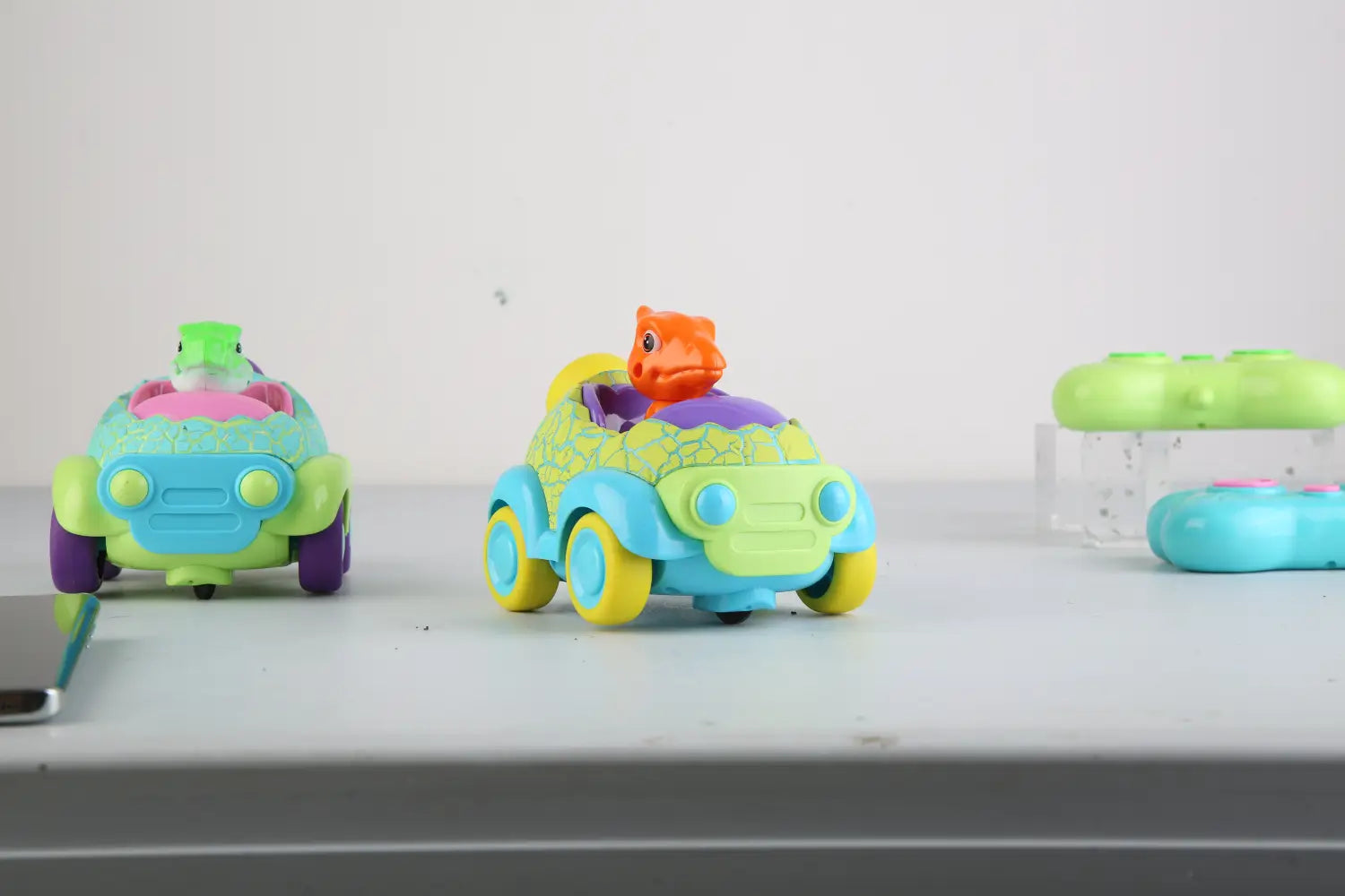 dinosaur remote control cars 2 pack for toddlers featuring brightly colored plastic toy cars with green blue and yellow accents.