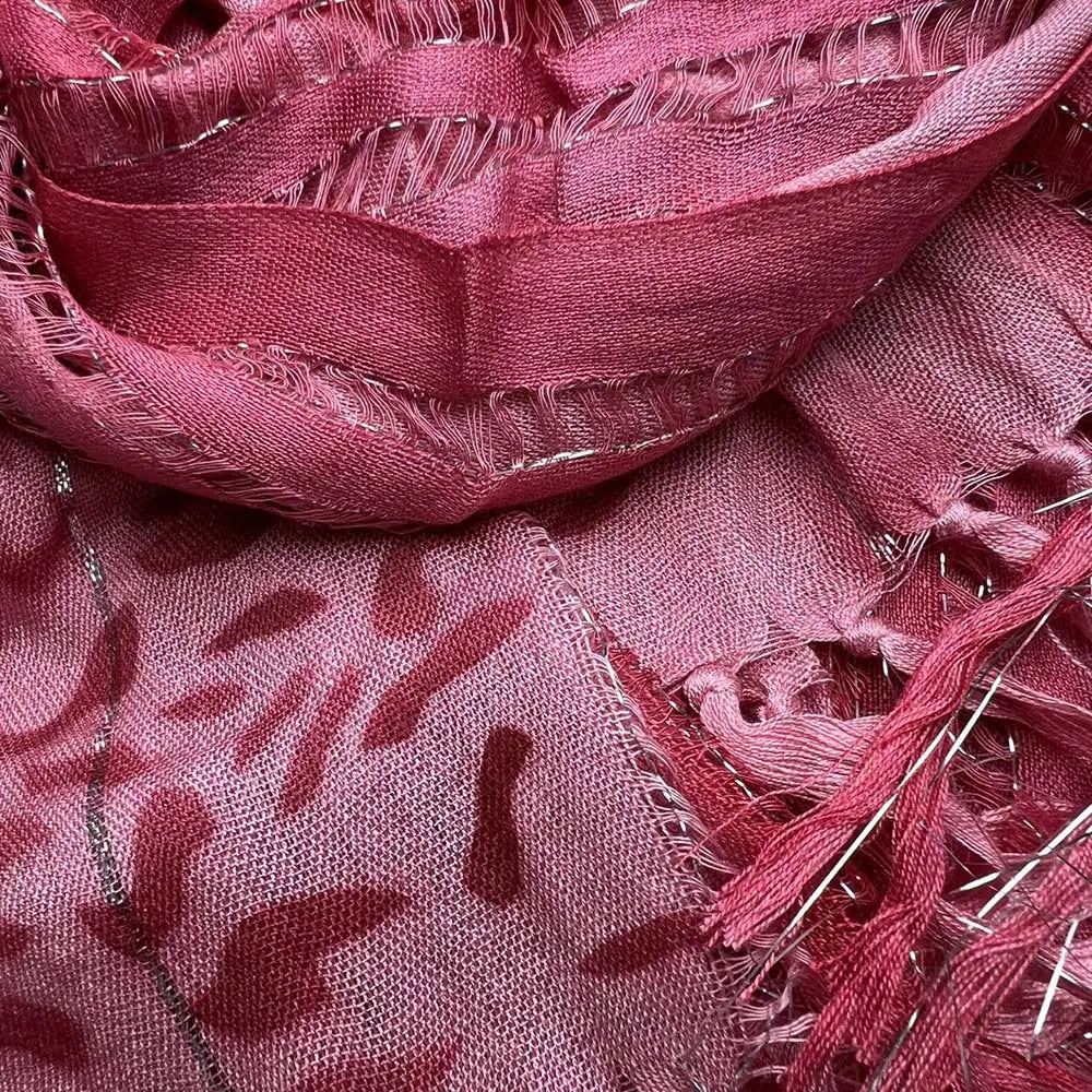 Un foulard en viscose rose poudré tacheté de léopard, avec des fils métalliques, présentant un motif discret et des bords effilochés.