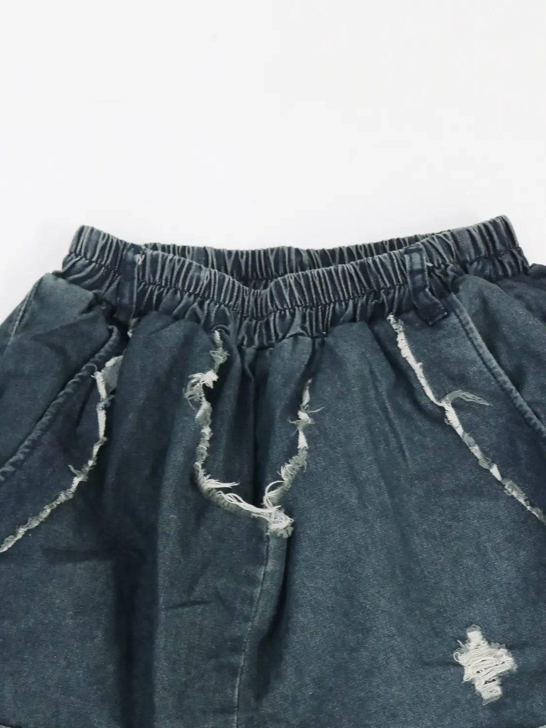 Dunkel gewaschene Jeansshorts mit ausgefranstem, abgenutztem Design und elastischem Bund, dargestellt in bestickten Patchwork-Jeans-Haremshosen.
