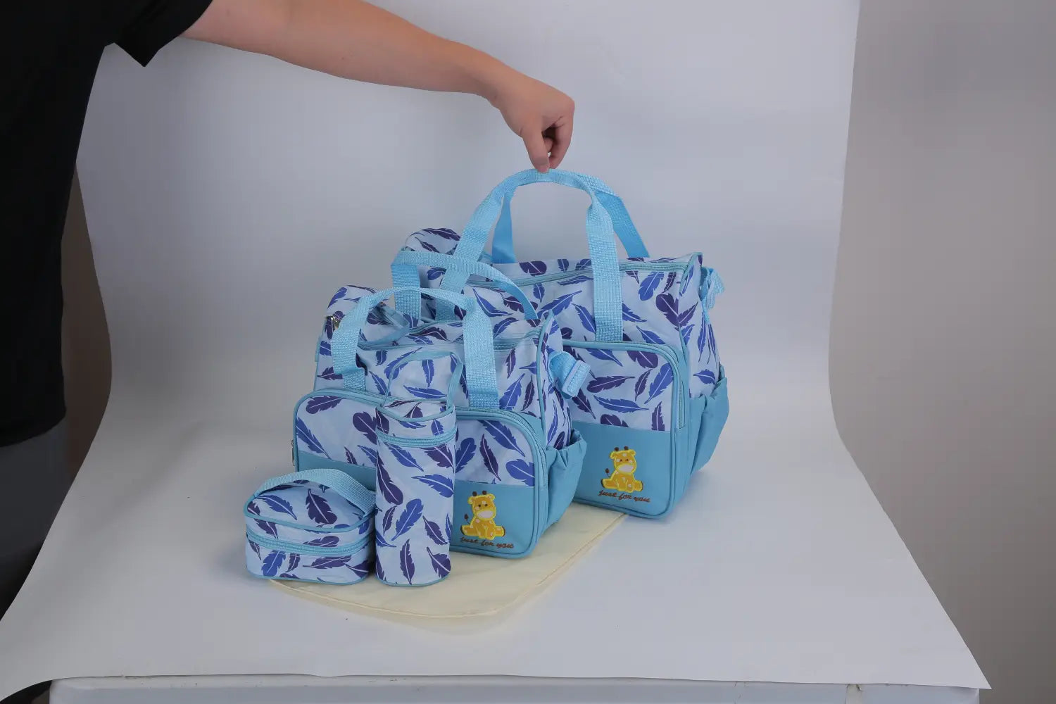 Light blue 5 piece patterned baby diaper bag set with a leaf pattern and yellow bear appliqués including travel accessories.