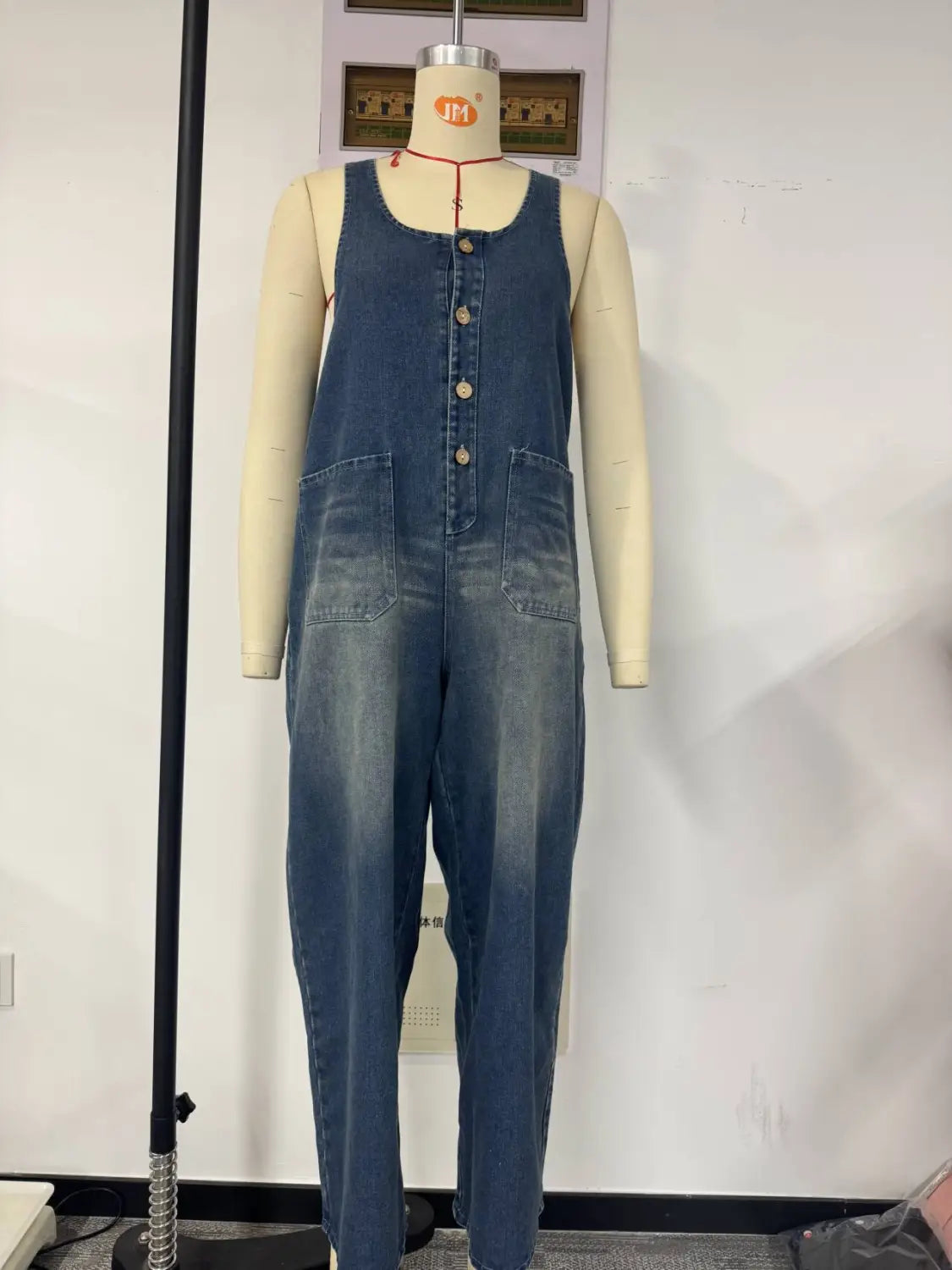 Combinaison salopette en denim bleu à jambes larges rétro, avec un design à boutons à l’avant et deux poches avant.