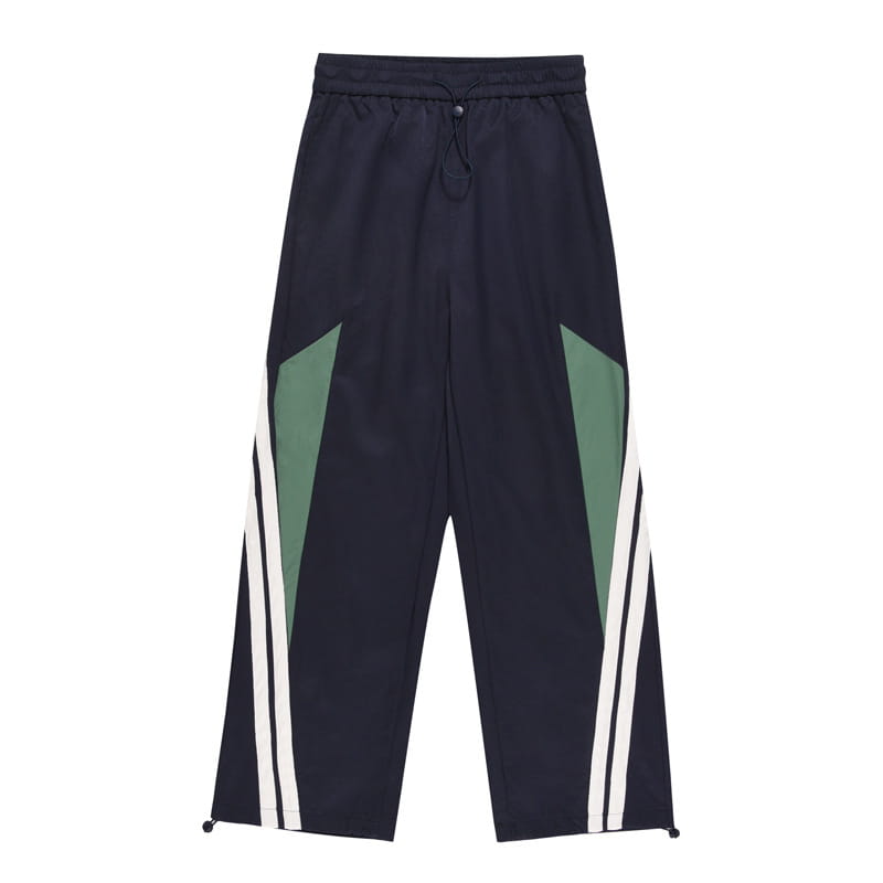 Men’s retro striped athletic track pants in dark navy with bold green and white diagonal stripes along the outer legs.