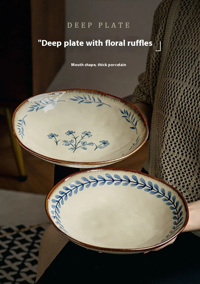 Cream-colored 9-inch ceramic deep plate with blue floral ruffles and brown rim featuring a blue leaf pattern.