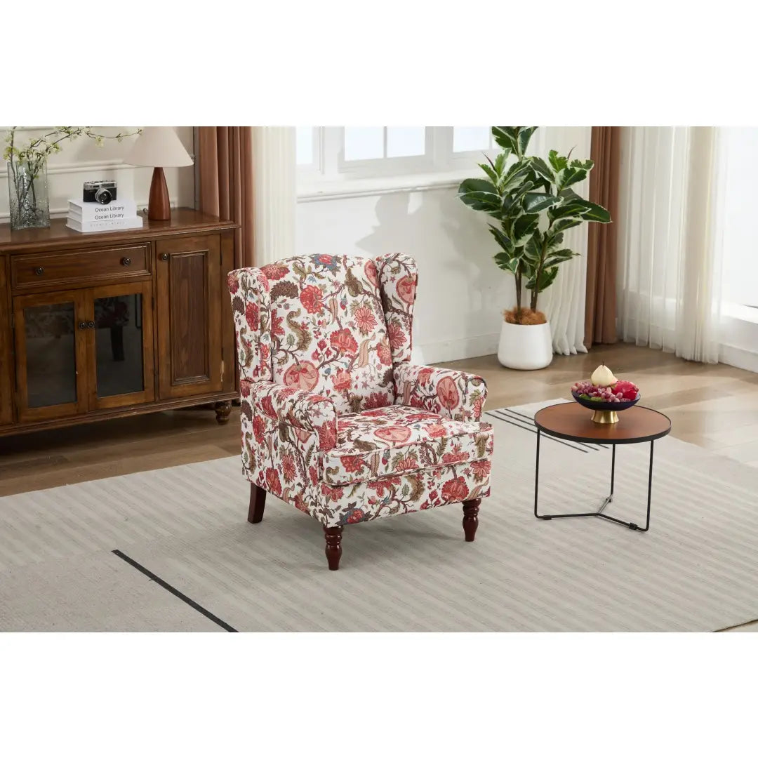 Una silla tipo ala con respaldo capitoné floral, tapizada en un tejido suave de color rojo y crema, con un patrón floral y patas de madera oscura marrón retro.