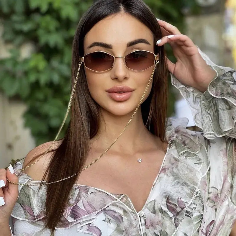 Gold-rimmed women’s octagonal sunglasses with brown gradient lenses and a delicate chain strap.