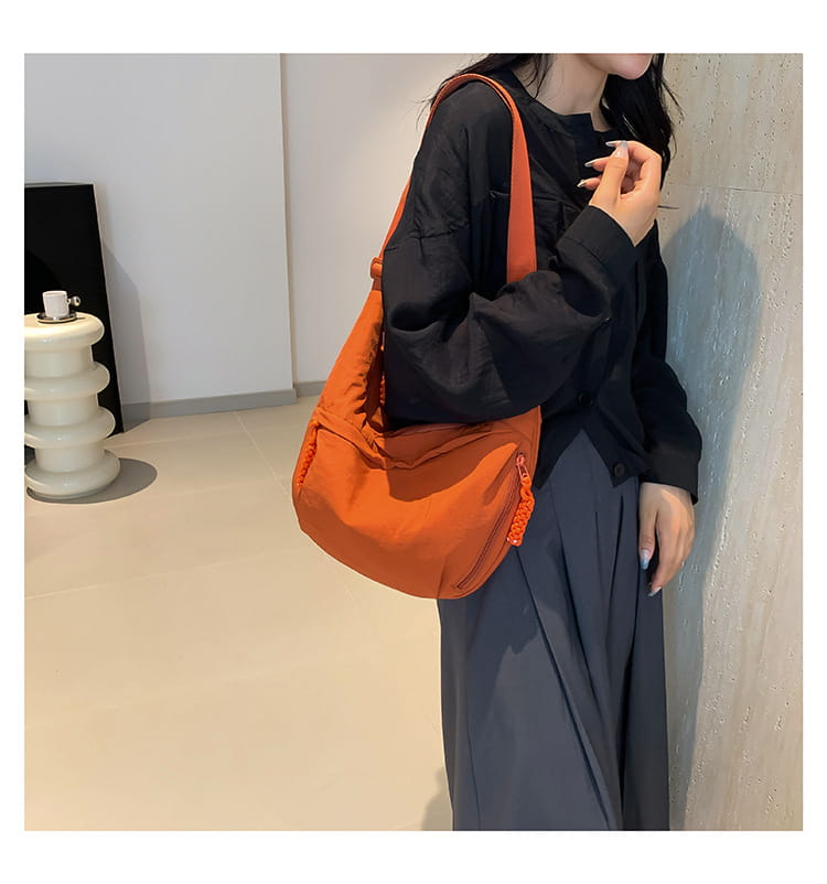 Orange canvas nylon crossbody bag with large capacity hobo shoulder bag design featuring a textured zipper pull and matching strap.