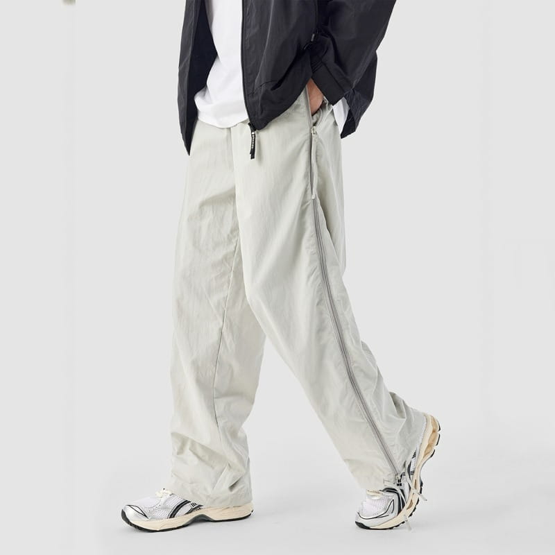 Pantalon de randonnée utilitaire à panneau latéral en mesh beige clair, présentant une conception cargo à jambe large, avec une fermeture éclair latérale sur toute la longueur et des détails de surpiqûres discrets.