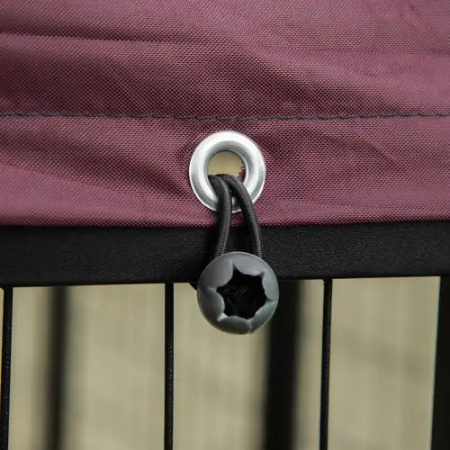 Un conmutador con forma de estrella negra adherido a una lona de tela color burdeos, con un ojal de metal plateado, en una perrera exterior con soporte giratorio para el cuenco