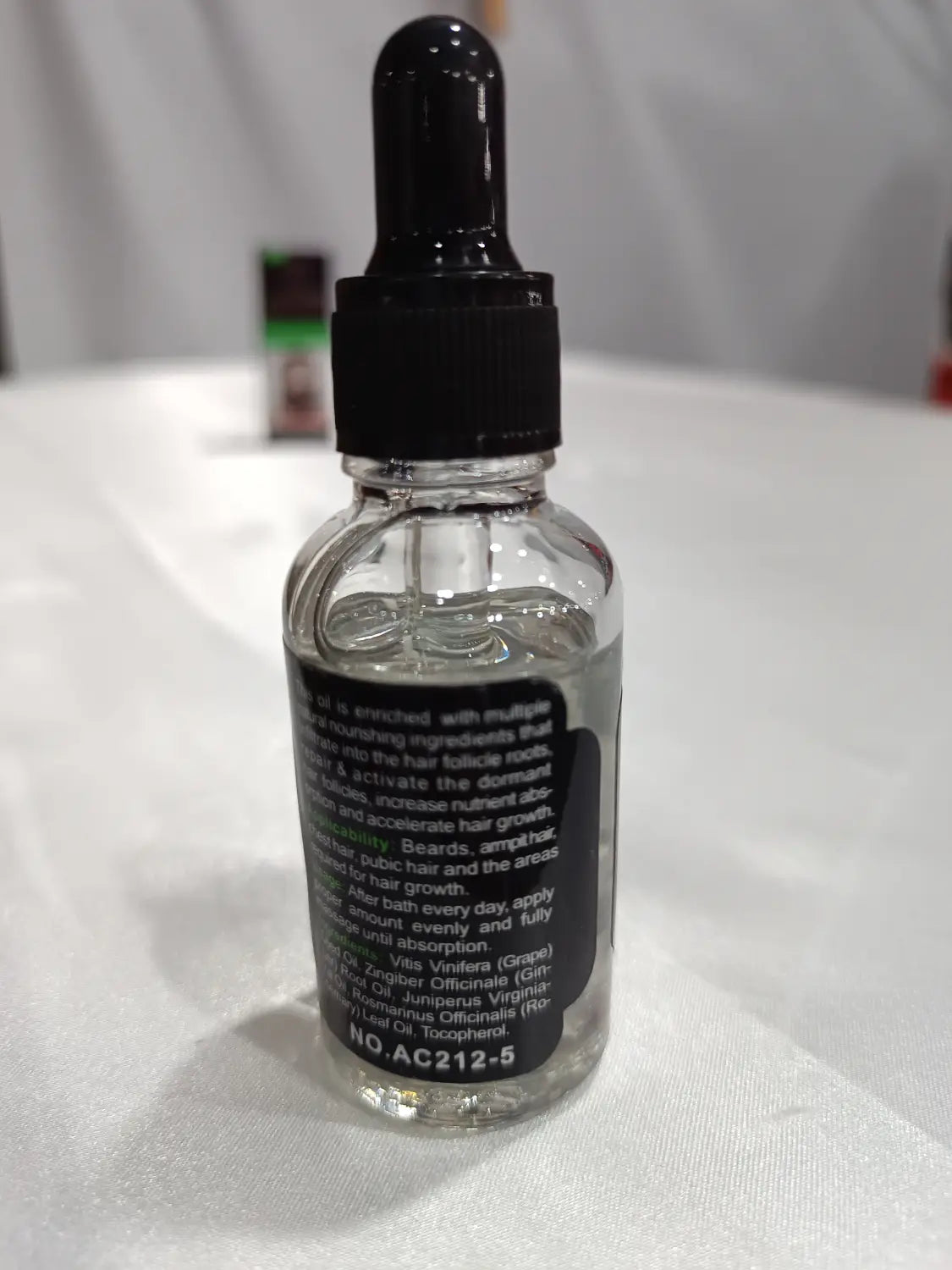 Clear glass bottle with black dropper cap and label containing transparent beard growth oil for natural repair and nourishing care.