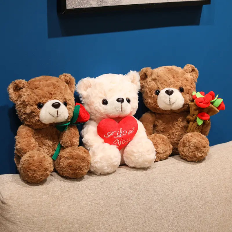Drei Plüsch-Teddybären in Weiß und Braun halten rote Rosen oder mit „I love you“ bestickte Herzen als Valentinsgeschenk, 16–25 cm.