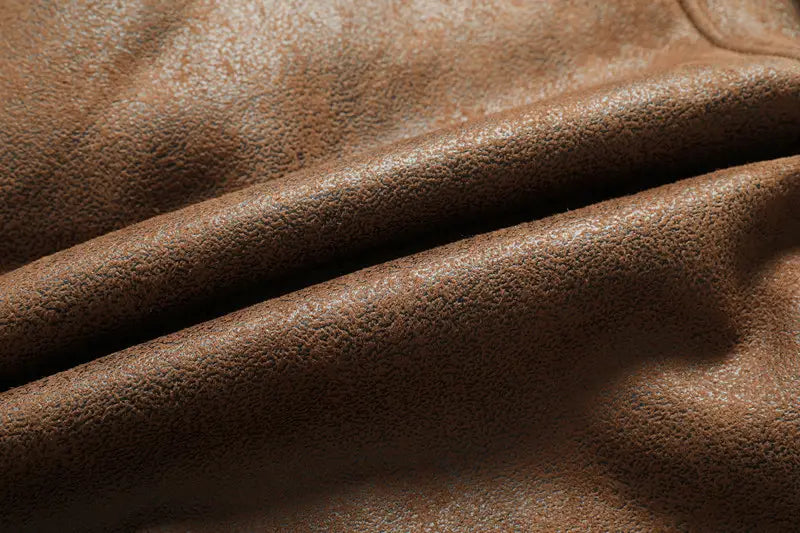 Cuir marron avec surface douce texturée et plis naturels sur la veste en denim doublée de polaire d’hiver pour homme, en peau de mouton.