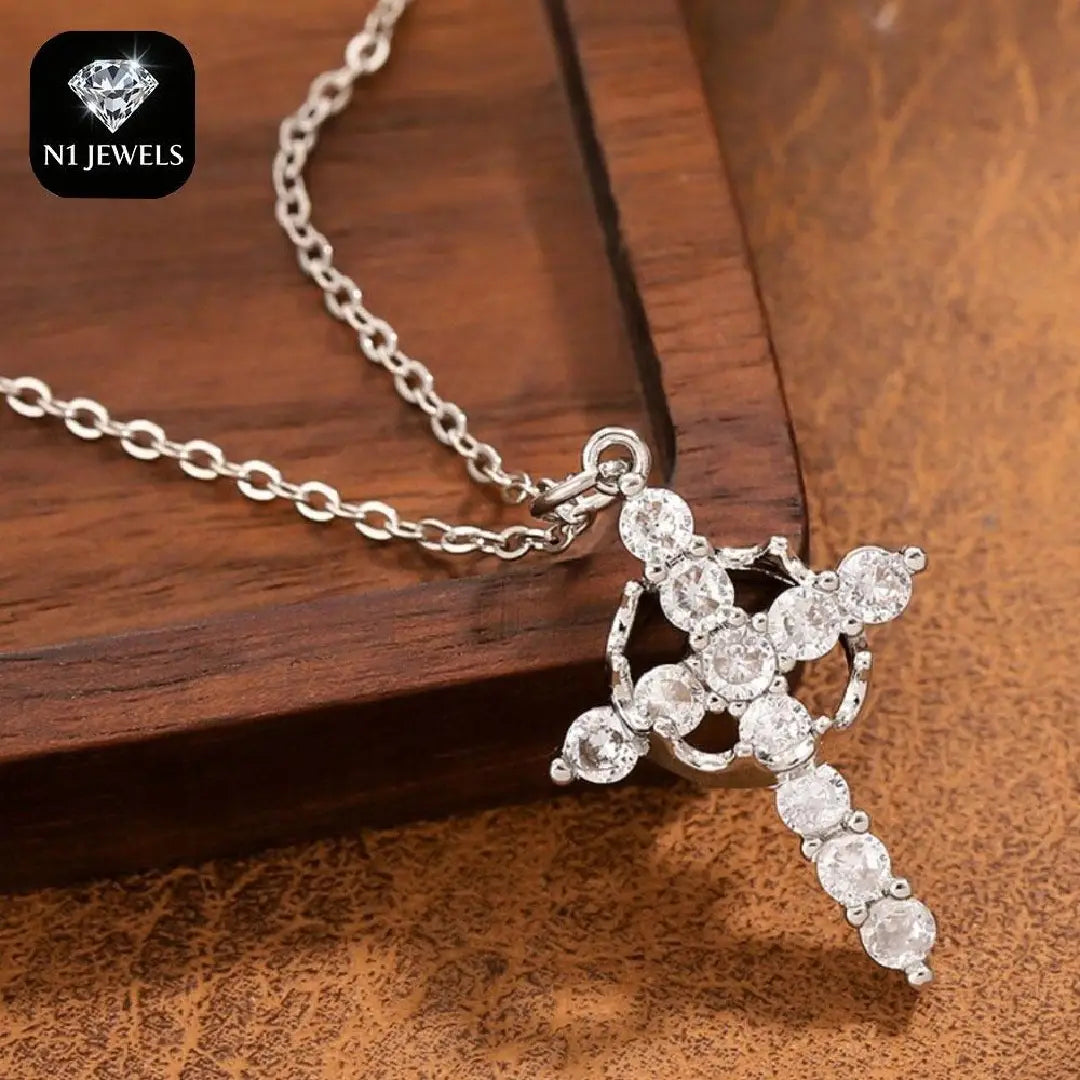 A sparkling layered crown and cross pendant necklace featuring a silver cross adorned with clear faceted stones on a delicate chain.