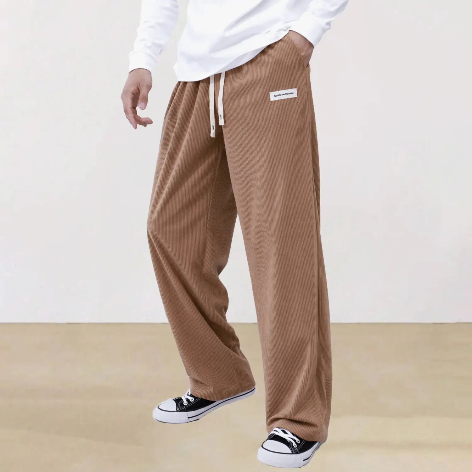 Men’s slim fit corduroy sporty drawstring casual pants in warm tan with vertical ribbed texture and white drawstring waistband.