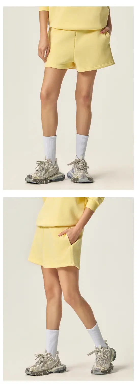 イエローの女性用コットンのカジュアルショートパンツで、フリース素材とサイドポケットを備え、ゆったりとしたフィット感があり、トレンディなホットパンツに適しています。