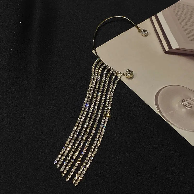 Silver-toned long drop ear cuff adorned with multiple strands of sparkling clear rhinestones in a crystal tassel 14k gold plated design.