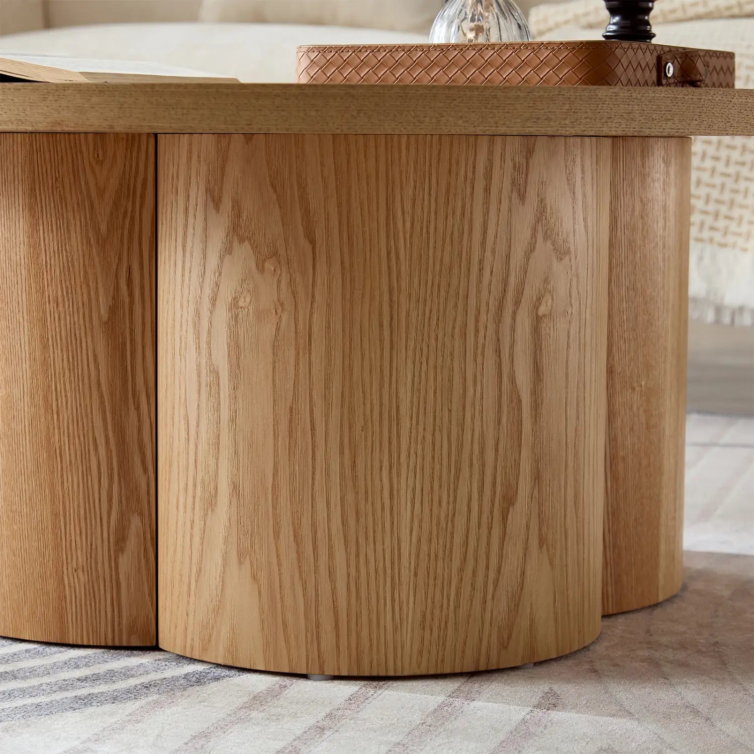 Mesa de centro redonda de madera de roble claro con una superficie superior lisa y una base de pedestal moderna segmentada y curva.