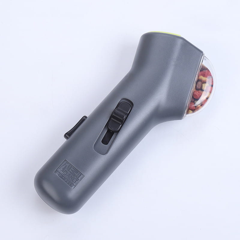 Lanceur de friandises pour chien portatif télécommandé en gris, jouet pour animal de compagnie, tête sphérique transparente contenant des grains de poivre colorés et des commandes en plastique noir