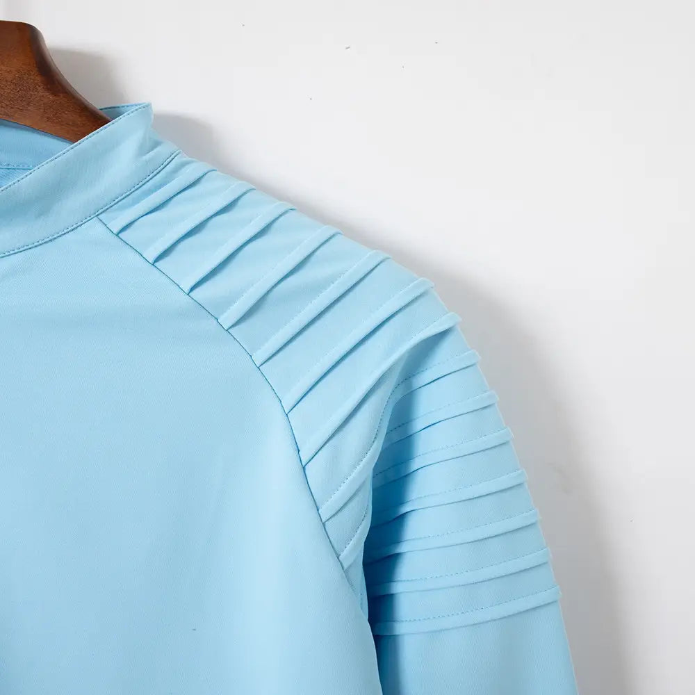 Hellblaues Herren-Quarter-Zip-Athletik-Poloshirt mit plissierten Ärmeln aus glattem, strukturiertem Stoff.