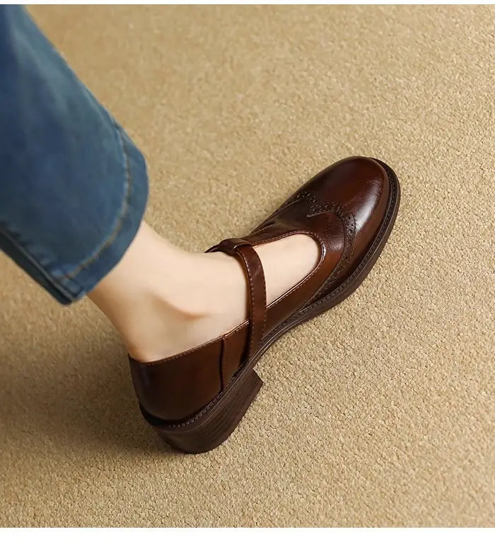 Braune Mary-Jane-Pumps mit klobigem Absatz aus Leder mit niedrigem Blockabsatz und dekorativer Brogue-Verzierung.