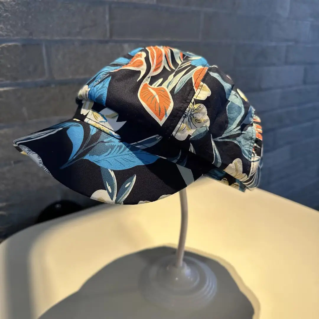 A vibrant floral-patterned newsboy cap for women in black, blue, orange, and white fabric.